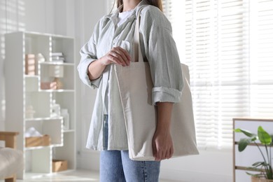 Photo of Woman with blank shopper bag indoors, closeup. Mockup for design