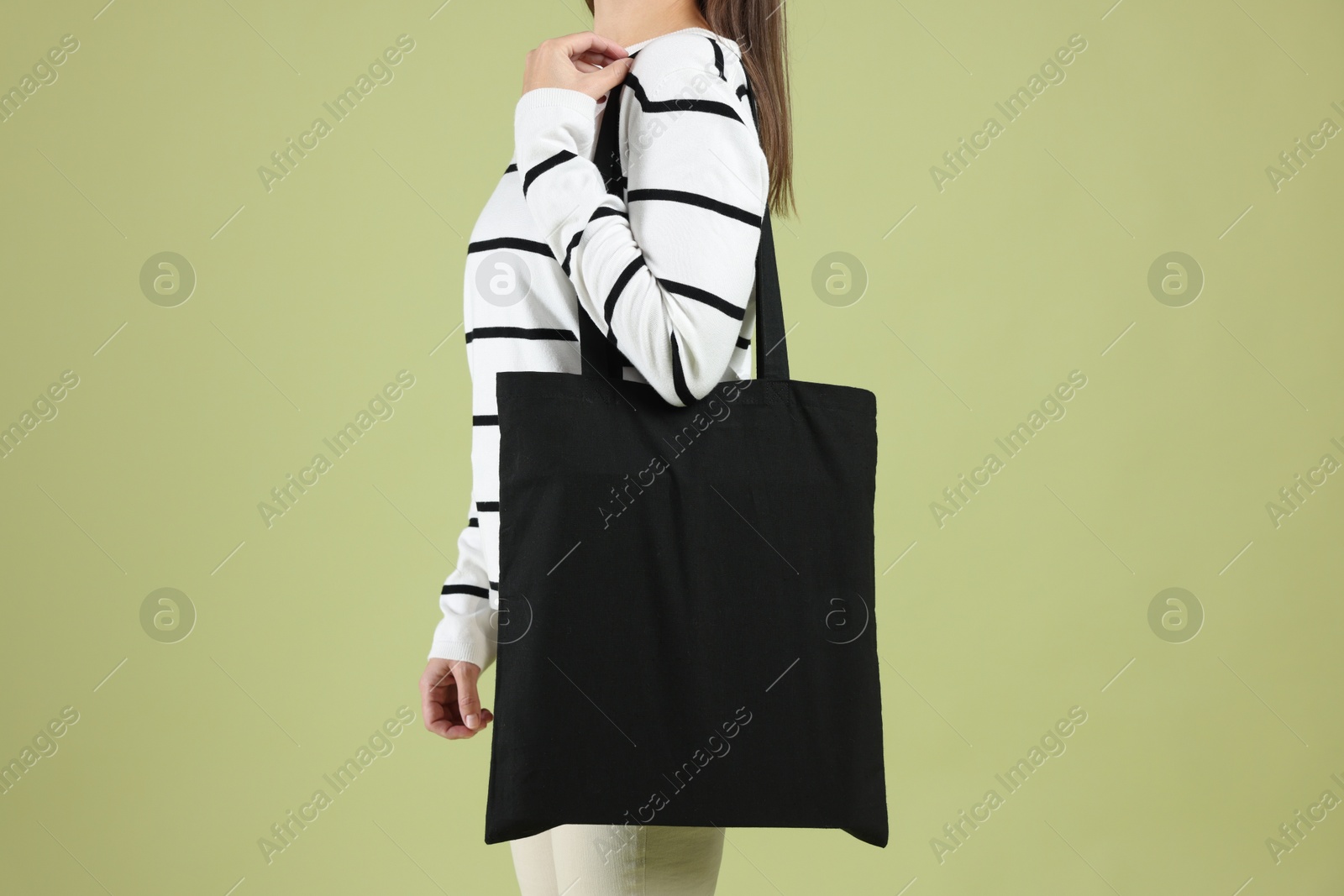 Photo of Woman with blank black shopper bag on color background, closeup. Mockup for design