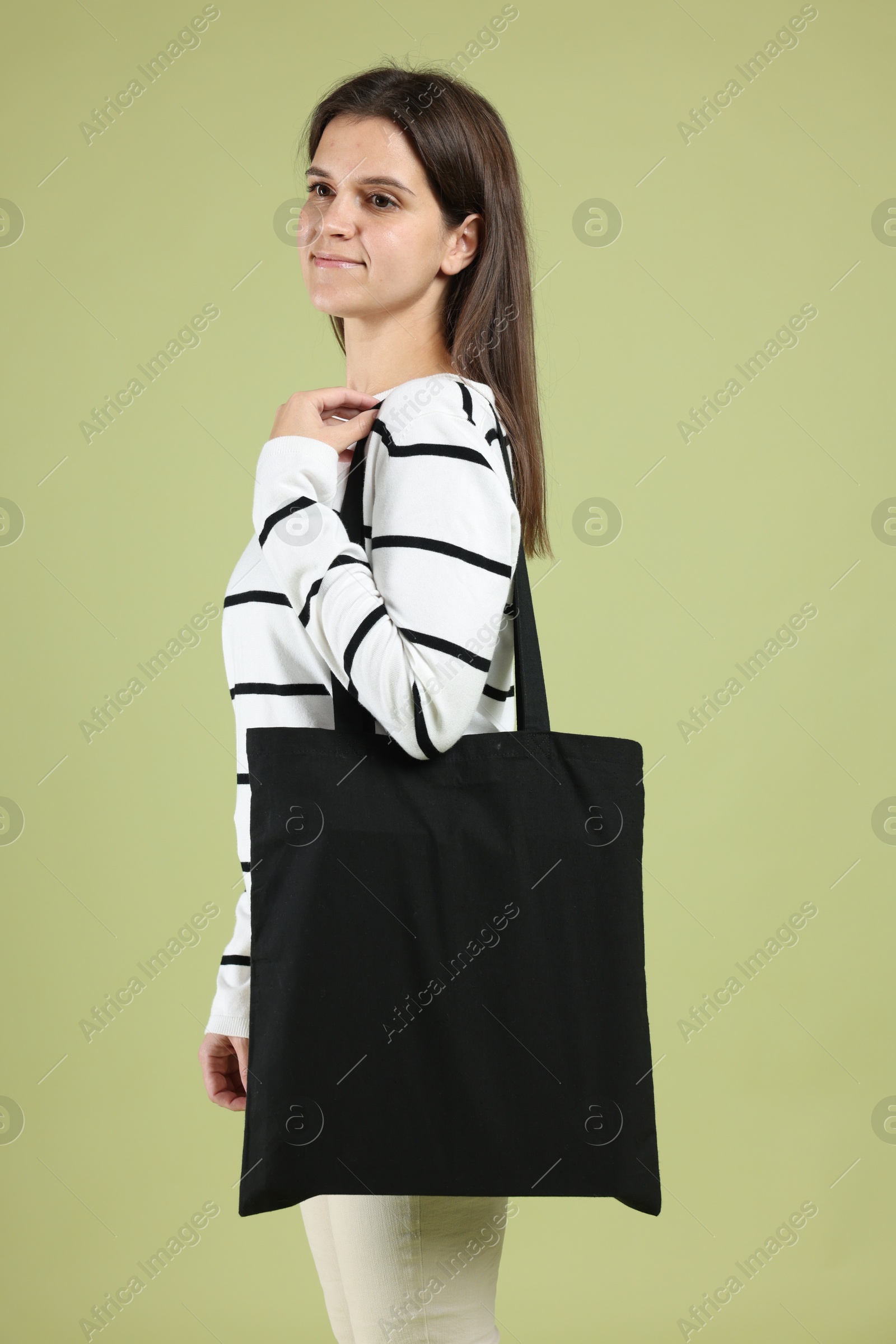 Photo of Woman with blank black shopper bag on color background. Mockup for design