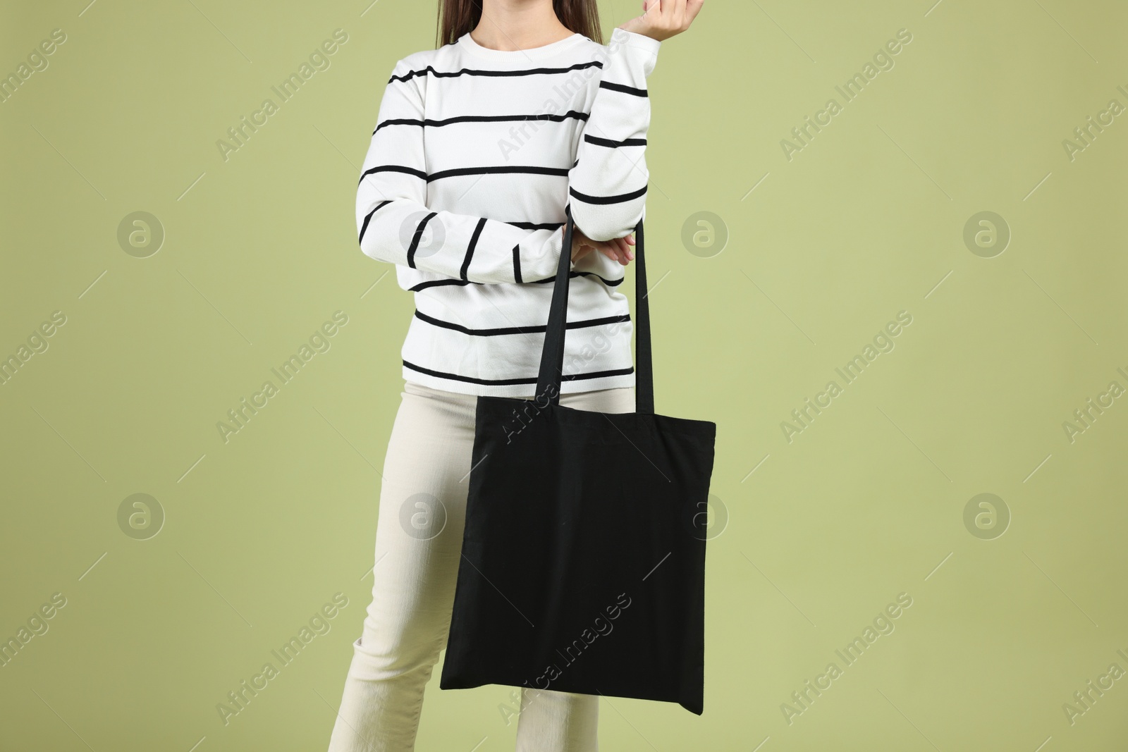 Photo of Woman with blank black shopper bag on color background, closeup. Mockup for design