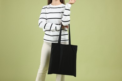 Photo of Woman with blank black shopper bag on color background, closeup. Mockup for design