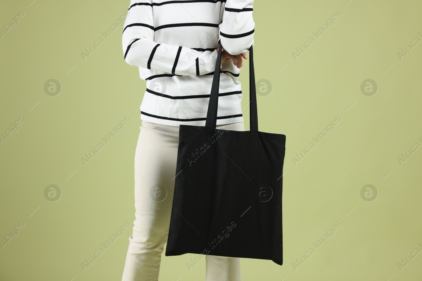 Photo of Woman with blank black shopper bag on color background, closeup. Mockup for design