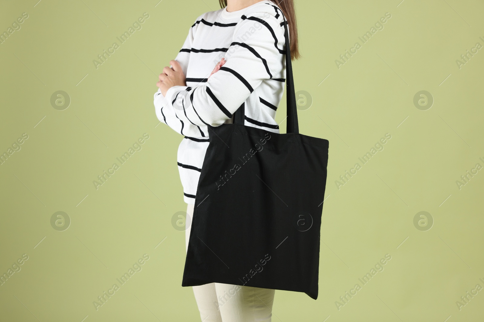 Photo of Woman with blank black shopper bag on color background, closeup. Mockup for design