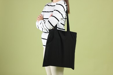 Photo of Woman with blank black shopper bag on color background, closeup. Mockup for design