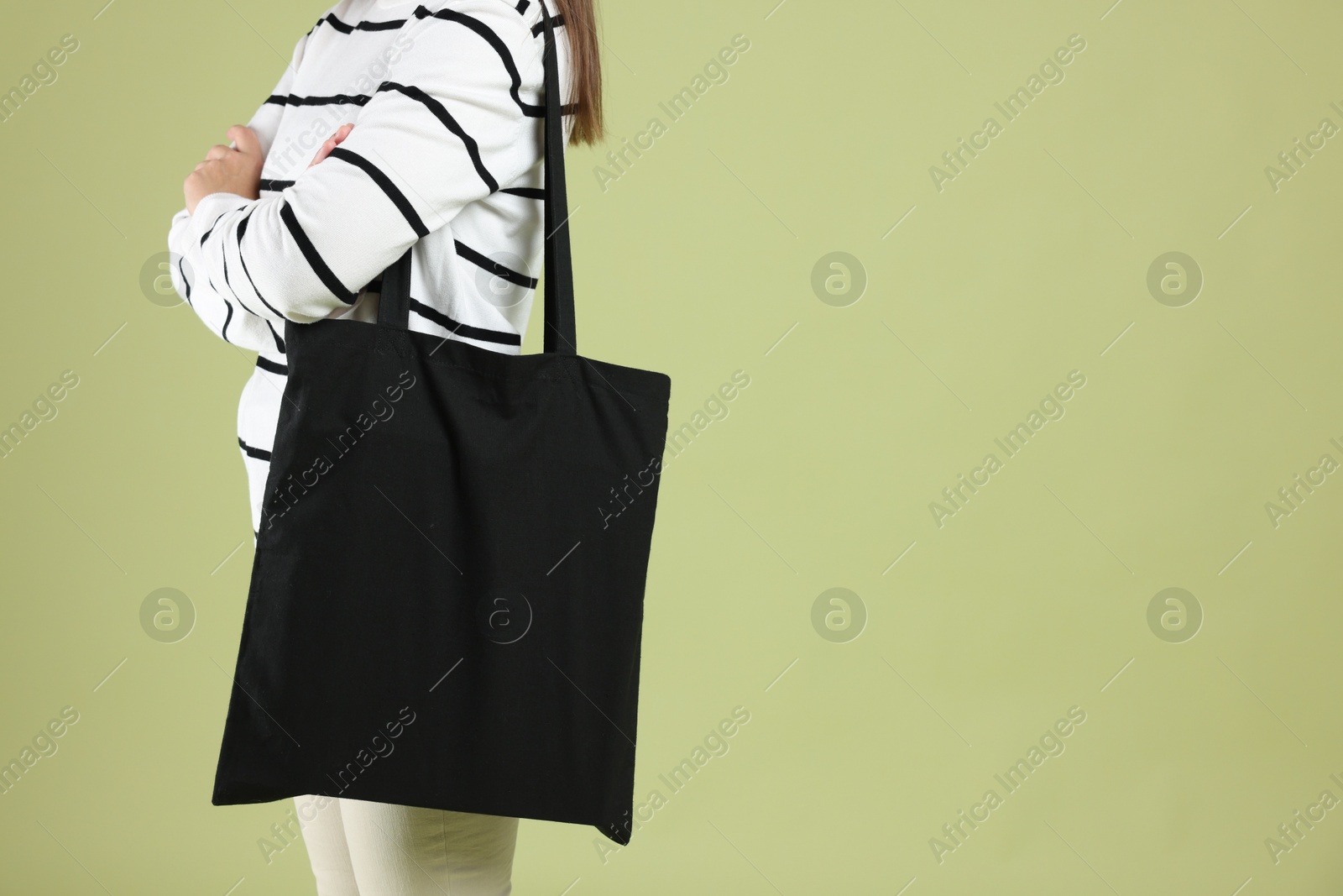 Photo of Woman with blank black shopper bag on color background, closeup. Mockup for design