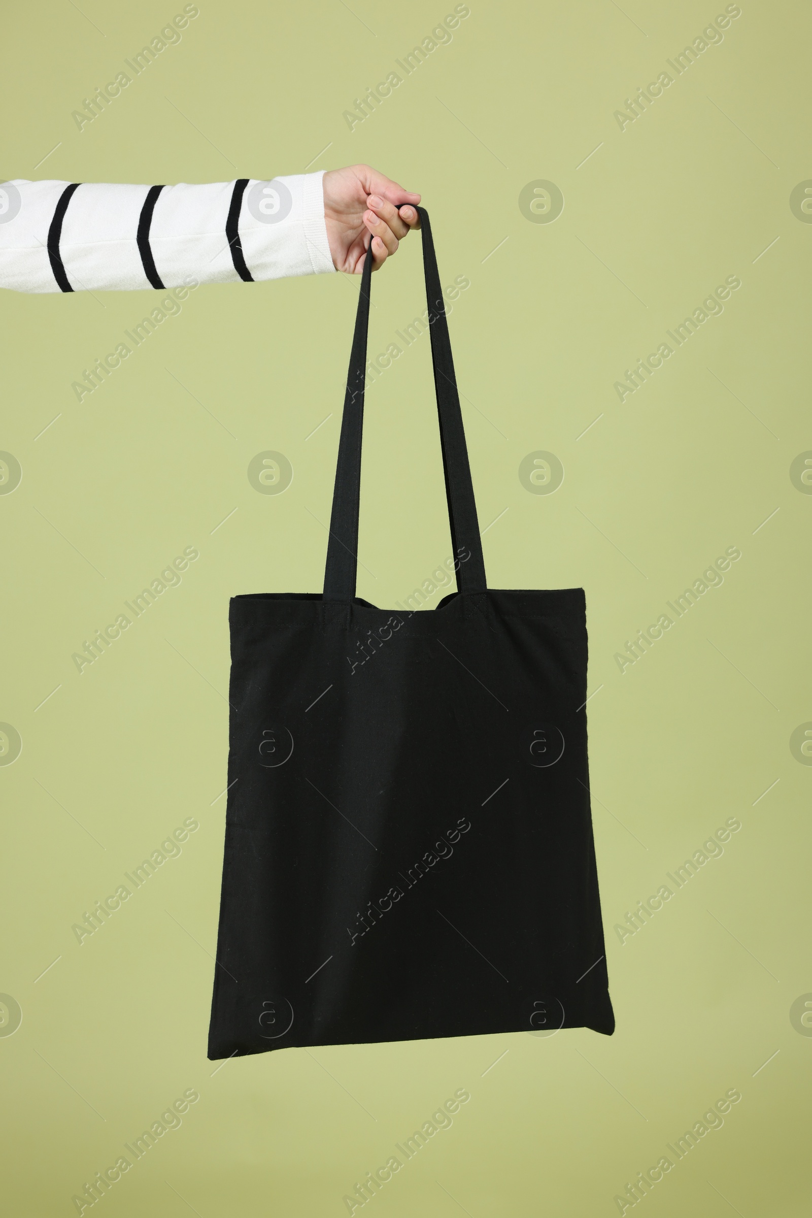 Photo of Woman with blank black shopper bag on color background, closeup. Mockup for design