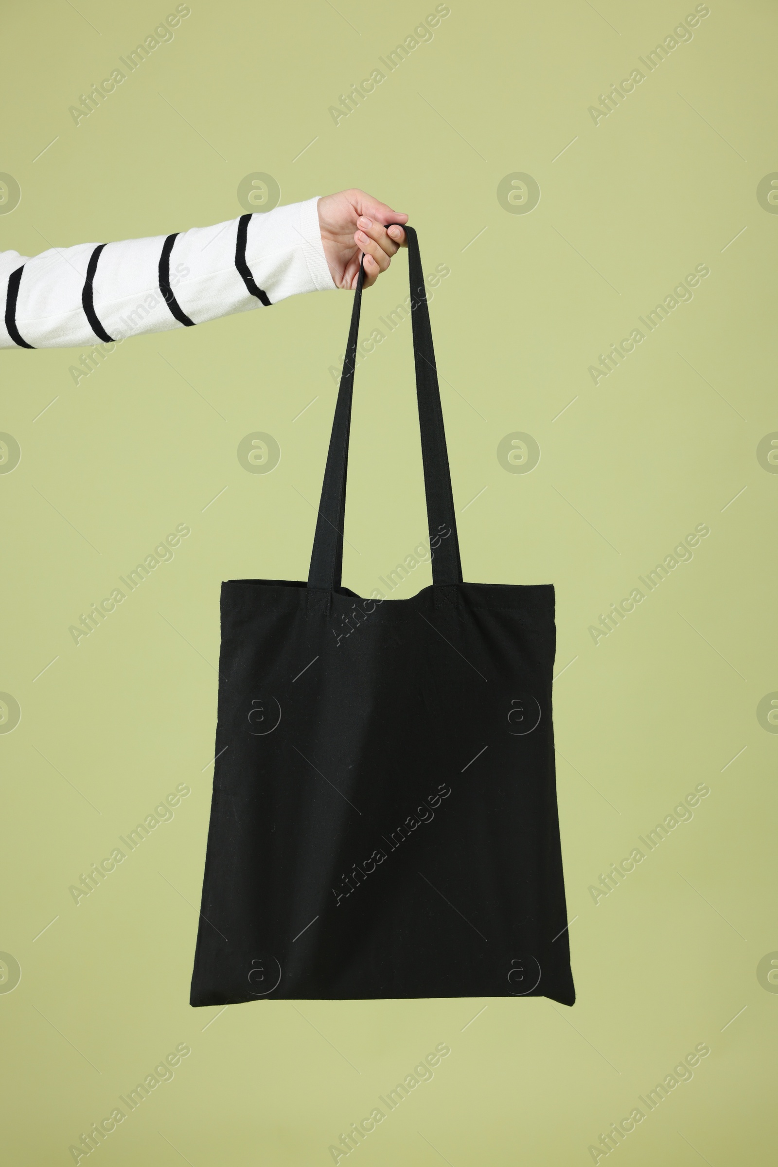 Photo of Woman with blank black shopper bag on color background, closeup. Mockup for design