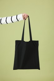 Photo of Woman with blank black shopper bag on color background, closeup. Mockup for design