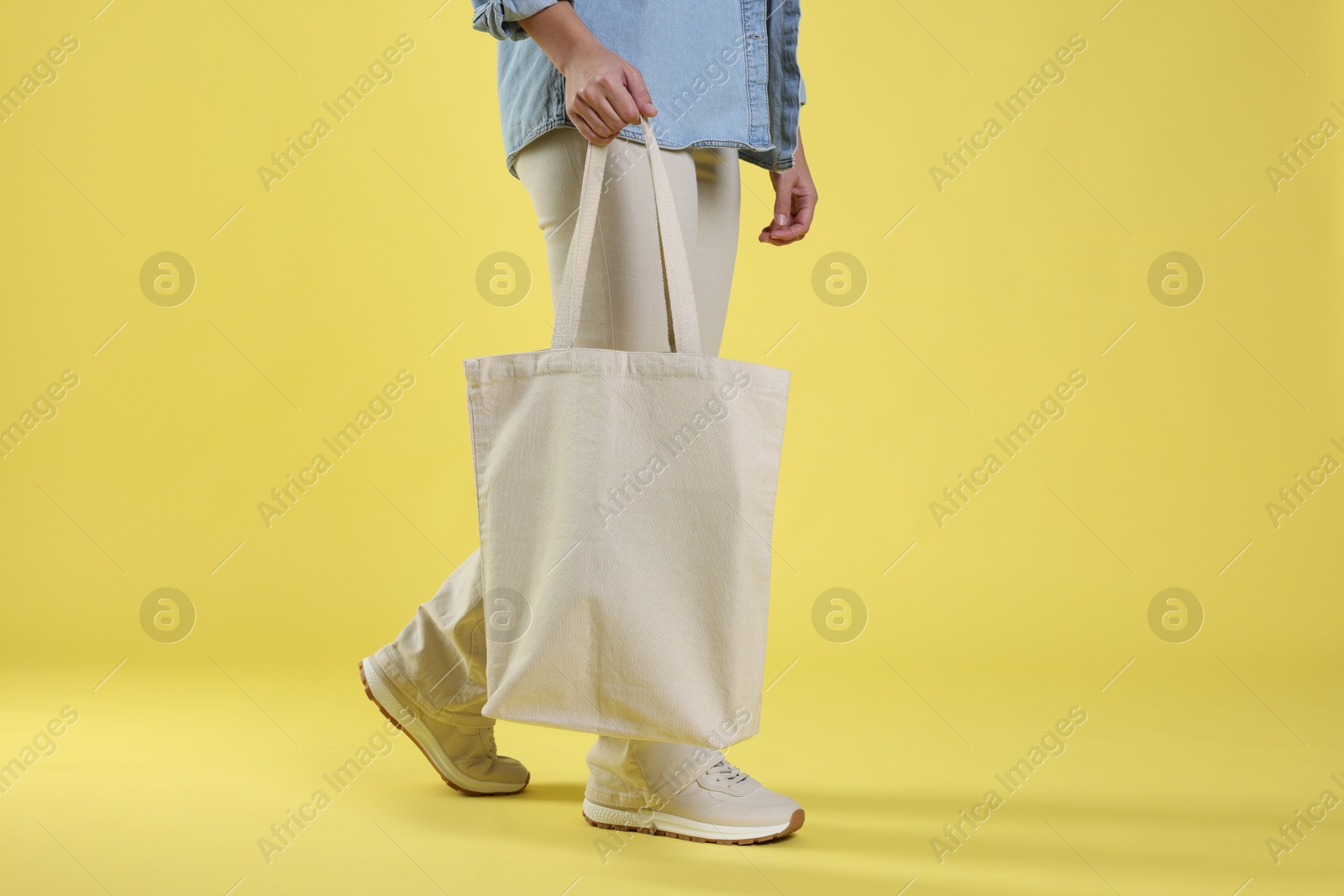 Photo of Woman with blank shopper bag on yellow background, closeup. Mockup for design