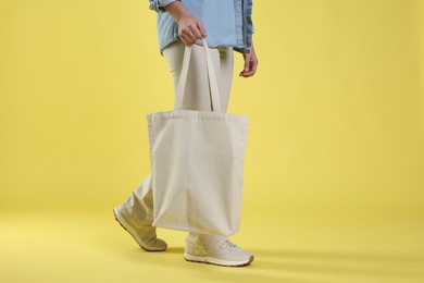 Photo of Woman with blank shopper bag on yellow background, closeup. Mockup for design