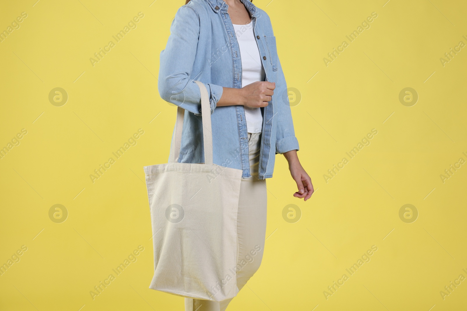 Photo of Woman with blank shopper bag on yellow background, closeup. Mockup for design