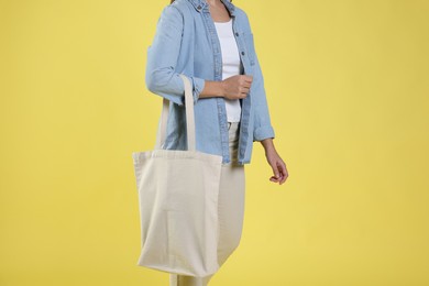 Photo of Woman with blank shopper bag on yellow background, closeup. Mockup for design