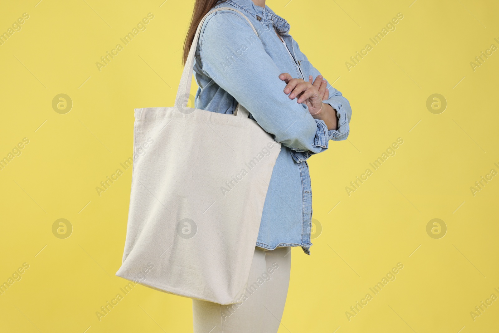 Photo of Woman with blank shopper bag on yellow background, closeup. Mockup for design