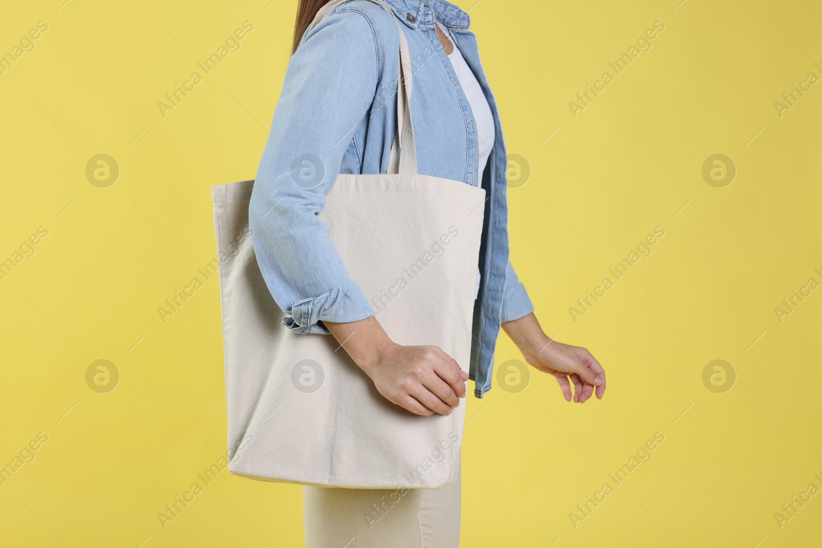 Photo of Woman with blank shopper bag on yellow background, closeup. Mockup for design