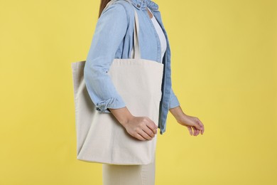 Woman with blank shopper bag on yellow background, closeup. Mockup for design