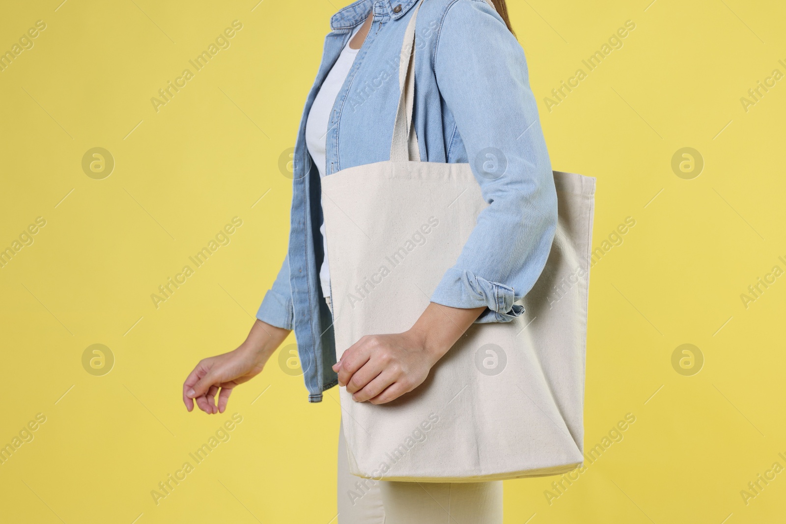 Photo of Woman with blank shopper bag on yellow background, closeup. Mockup for design