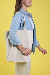 Photo of Woman with blank shopper bag on yellow background, closeup. Mockup for design