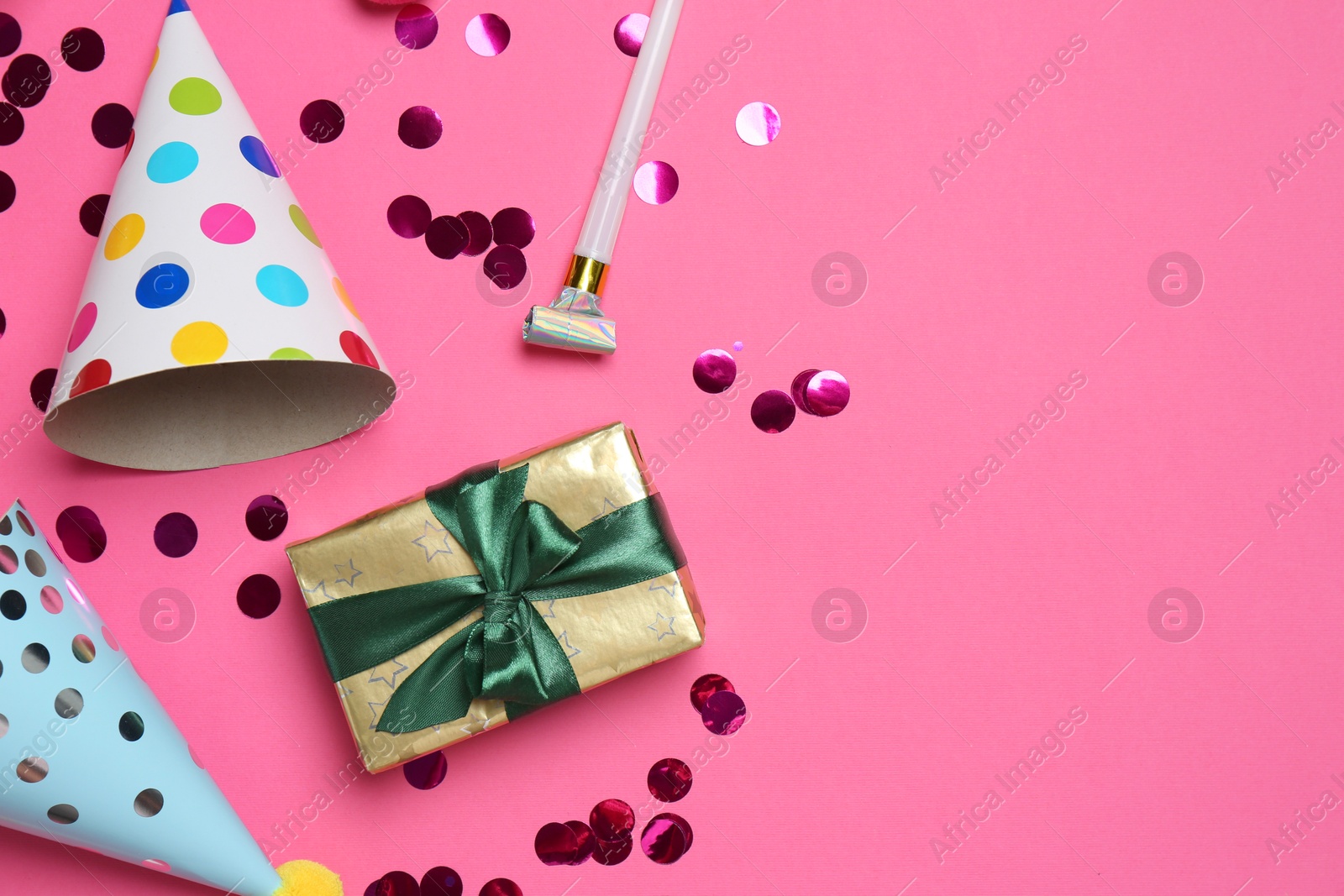 Photo of Shiny confetti and party decor on pink background, flat lay. Space for text