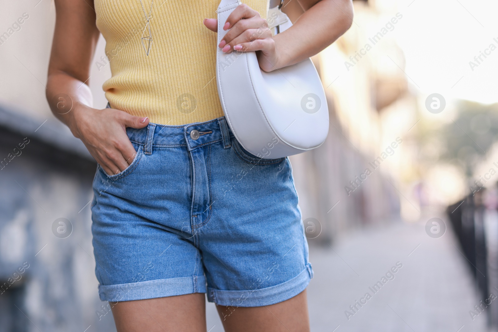 Photo of Woman with white bag wearing stylish denim shorts outdoors, closeup