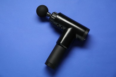 Photo of One black percussive massager on blue background, above view