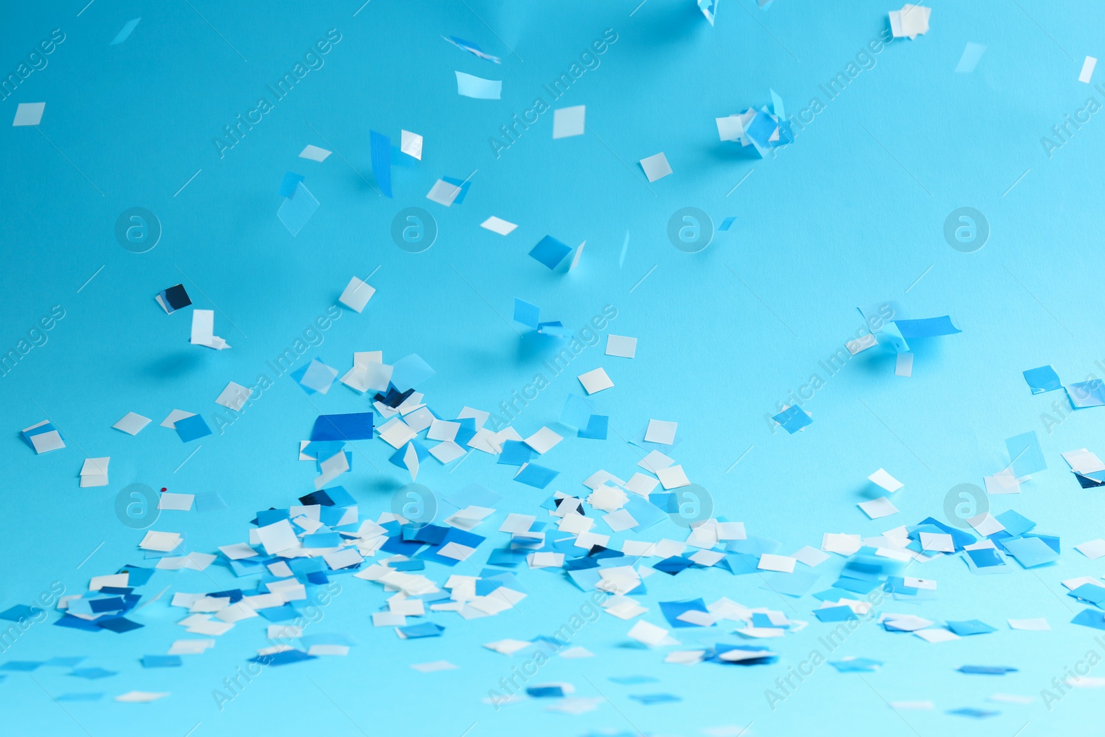 Photo of Beautiful confetti on light blue background, closeup