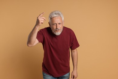 Photo of Portrait of senior man pointing on beige background