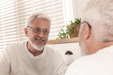 Photo of Senior man looking in mirror at home