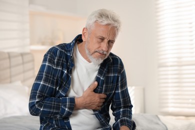 Photo of Senior man suffering from pain in chest at home