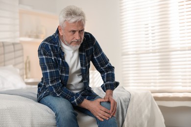 Photo of Senior man suffering from pain in knee at home