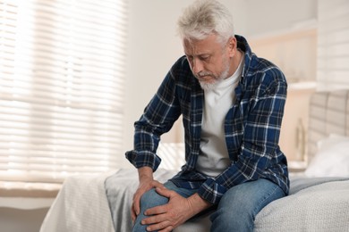 Photo of Senior man suffering from pain in knee at home