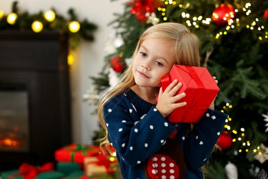 Photo of Little girl with Christmas gift at home, space for text