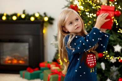 Photo of Little girl with Christmas gift at home, space for text