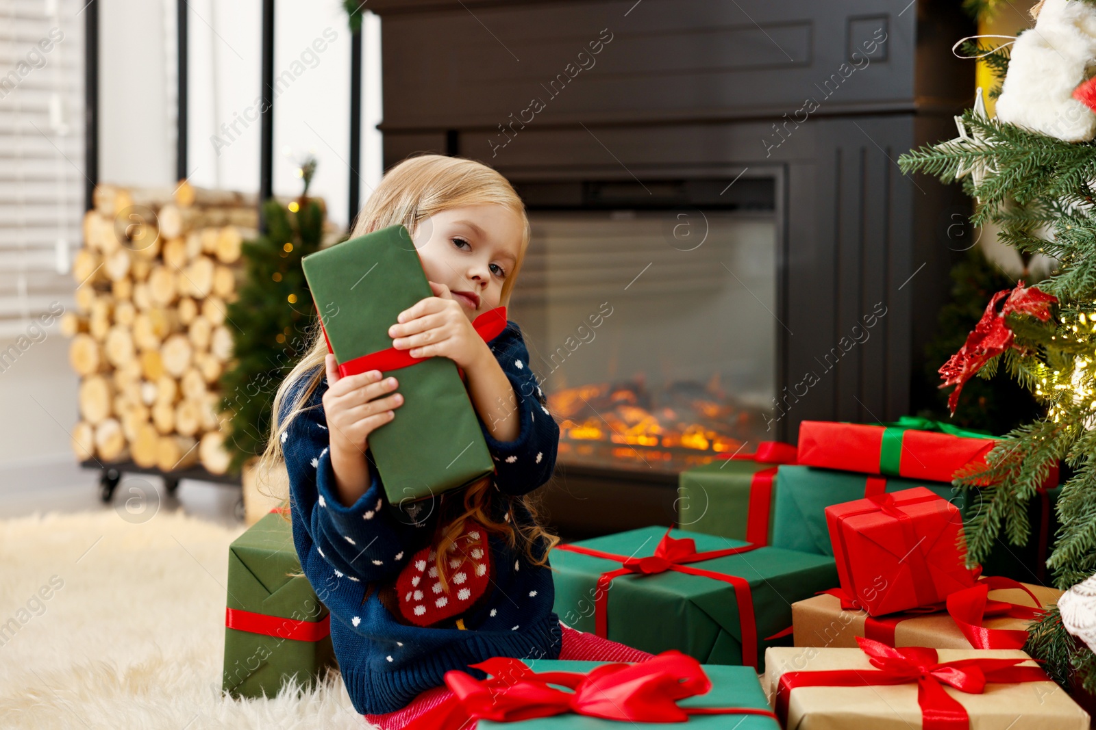 Photo of Little girl with Christmas gifts on floor at home