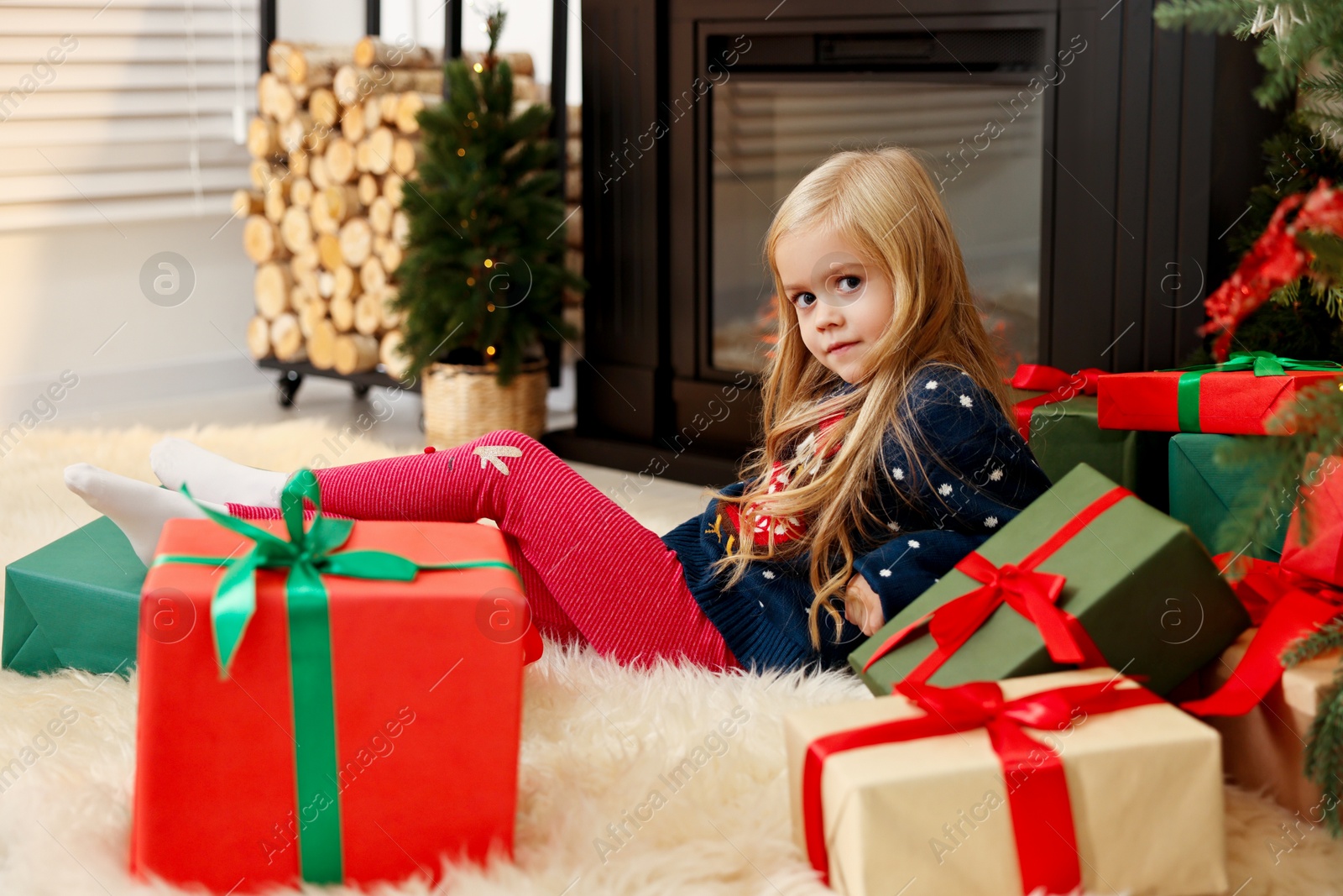 Photo of Little girl with Christmas gifts on floor at home