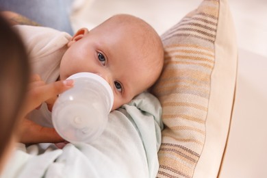 Photo of Mother feeding her cute baby indoors, closeup