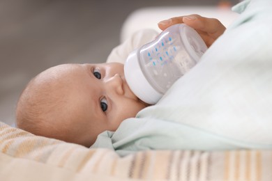 Photo of Mother feeding her cute baby indoors, closeup