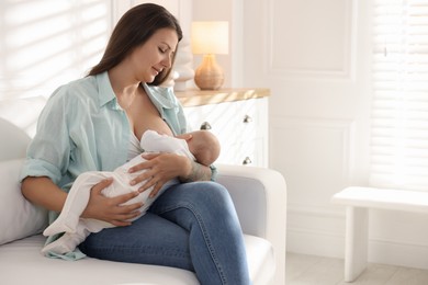 Photo of Mother breastfeeding her little baby on sofa at home