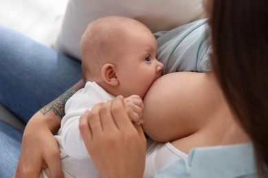 Photo of Mother breastfeeding her little baby at home, closeup