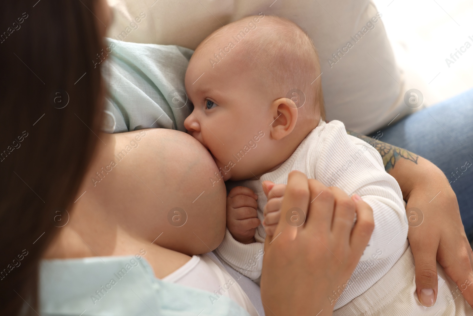 Photo of Mother breastfeeding her little baby at home, closeup