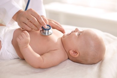 Photo of Pediatrician examining little child with stethoscope in clinic, closeup. Checking baby's health