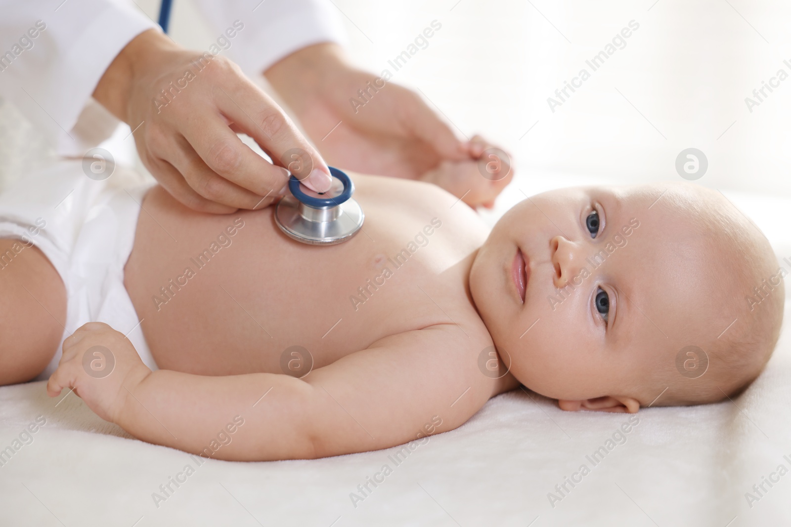 Photo of Pediatrician examining little child with stethoscope in clinic, closeup. Checking baby's health