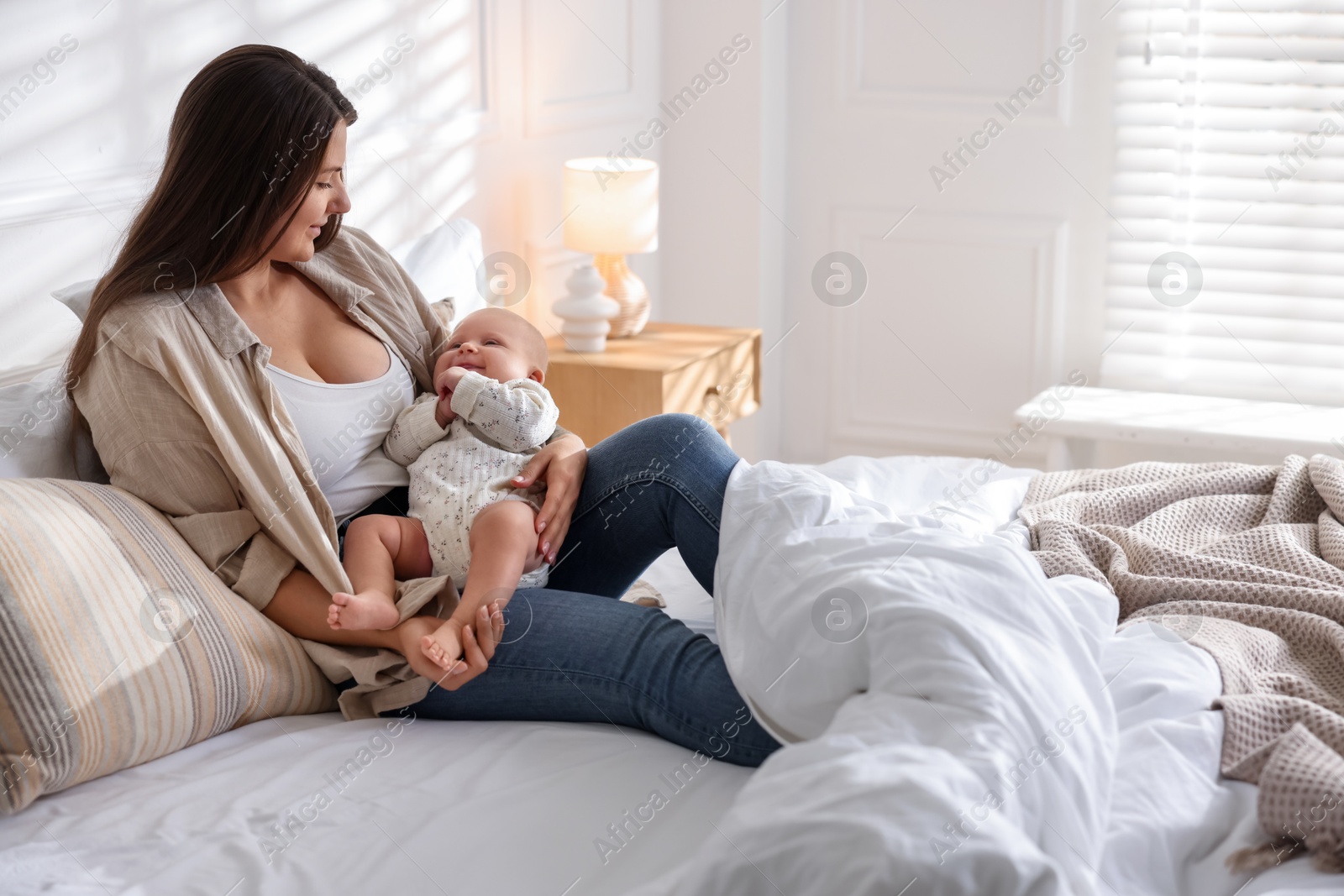 Photo of Mother with her cute little baby on bed at home