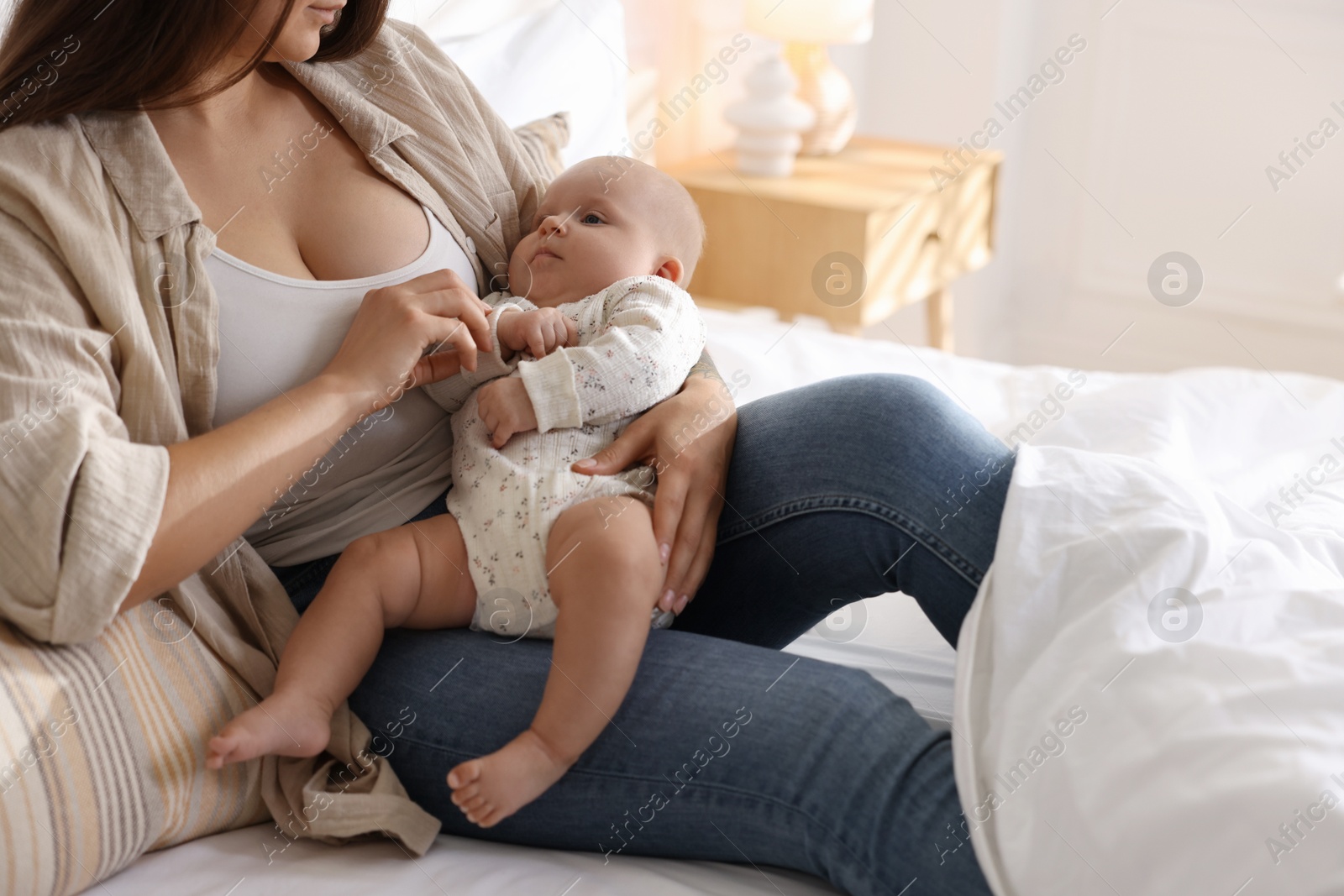 Photo of Mother with her cute little baby on bed at home, closeup