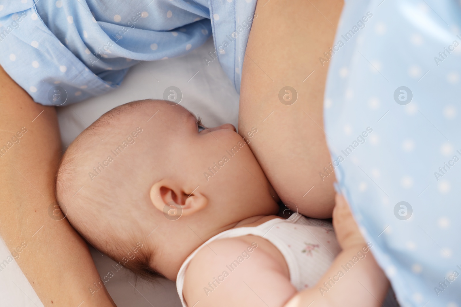 Photo of Mother breastfeeding her little baby on bed at home, closeup