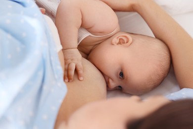 Photo of Mother breastfeeding her little baby on bed at home, closeup