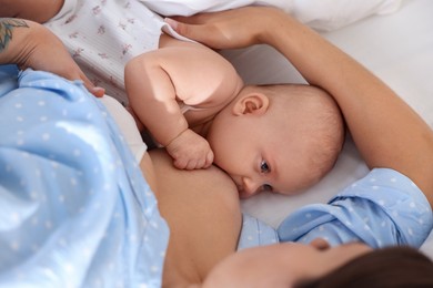 Photo of Mother breastfeeding her little baby on bed at home, closeup