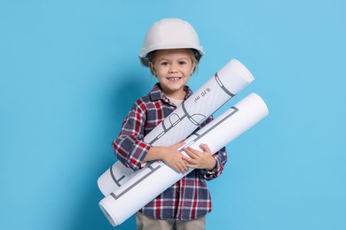 Photo of Little girl with house plan pretending to be architect on light blue background. Dreaming of future profession