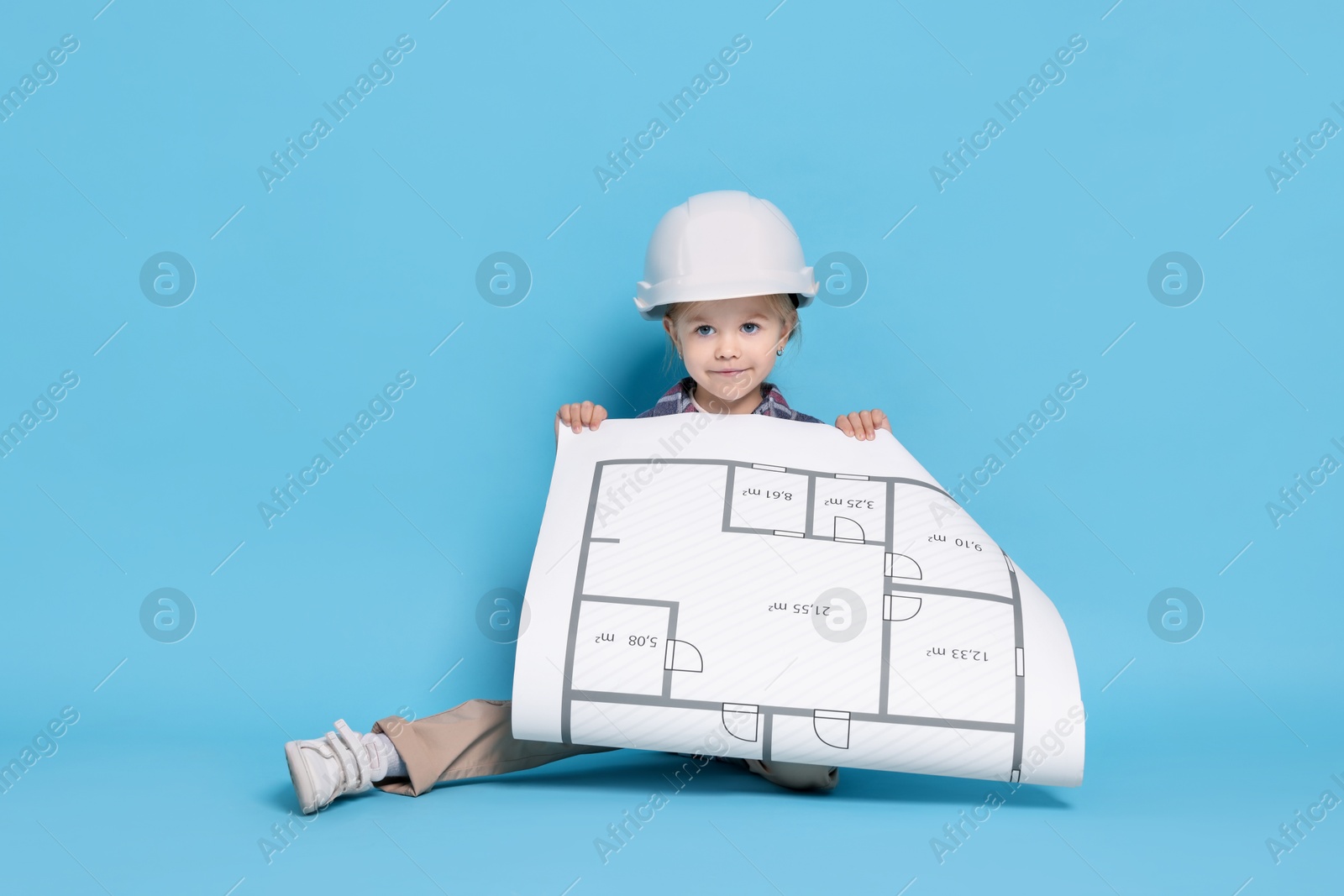 Photo of Little girl with house plan pretending to be architect on light blue background. Dreaming of future profession