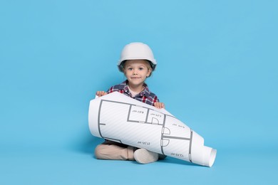 Photo of Little girl with house plan pretending to be architect on light blue background. Dreaming of future profession