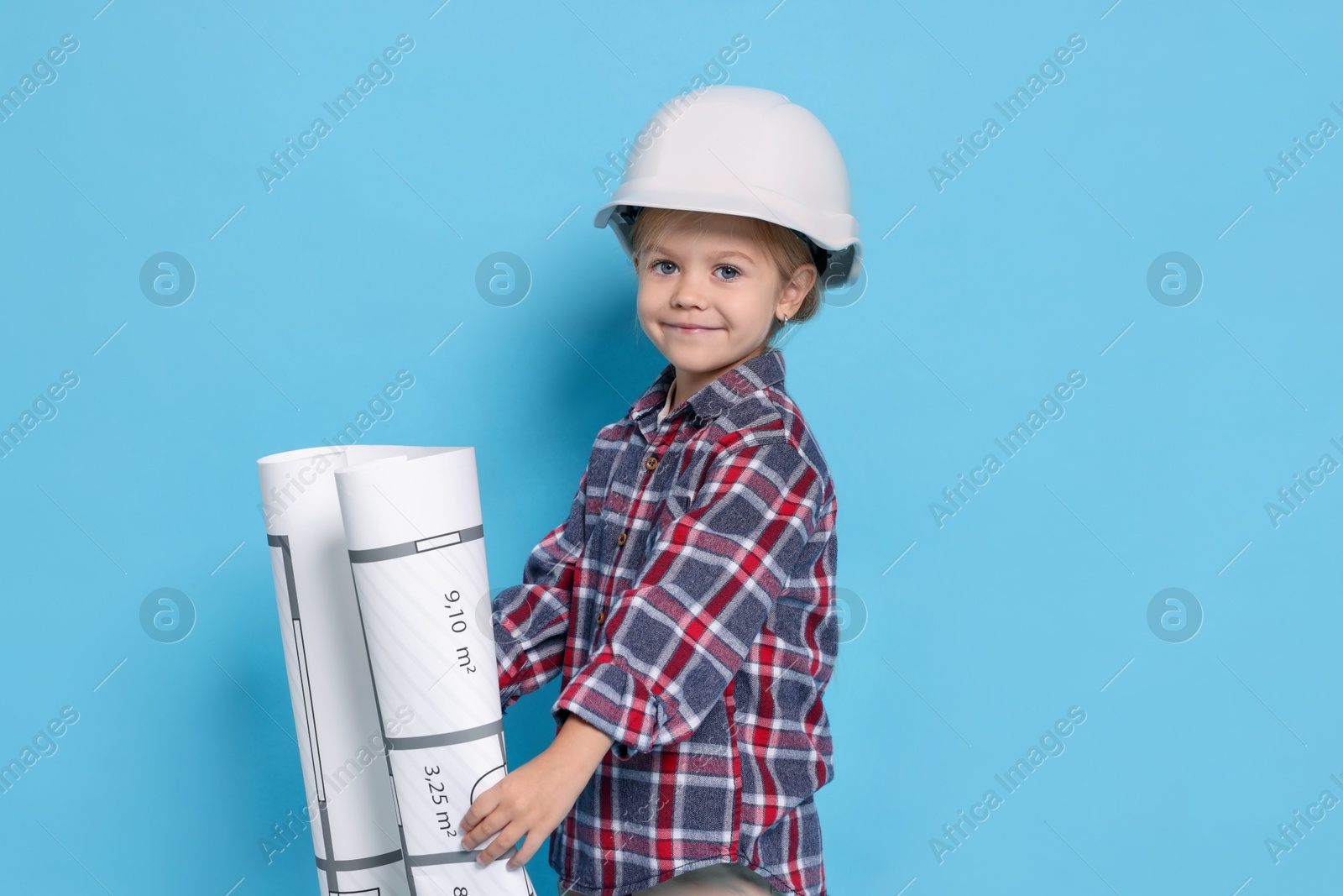 Photo of Little girl with house plan pretending to be architect on light blue background. Dreaming of future profession